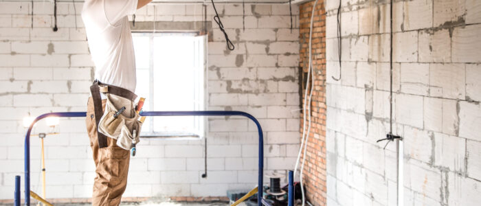 Electrician installer with a tool in his hands, working with cable on the construction site.